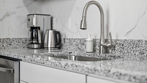Eine Küche mit einer Arbeitsplatte aus Granit, Edelstahlgeräten und einem modernen Wasserhahn.