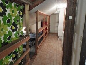 A dormitory room with bunk beds, a tiled floor, and a green floral curtain. - Mountain gîte under the roof facing the forest (Molines-en-Queyras)