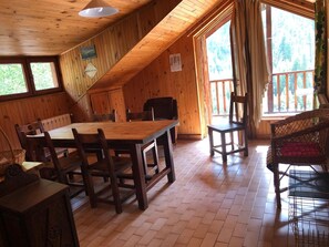 Une cabane en bois avec un coin repas, une grande fenêtre et une vue sur la forêt.