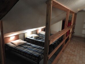 Une chambre de type dortoir, équipée de lits superposés, chacun ayant une tête de lit et un oreiller.