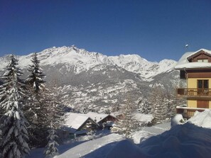 Eine verschneite Berglandschaft mit einem Chalet und einem Balkon mit Holzgeländern.