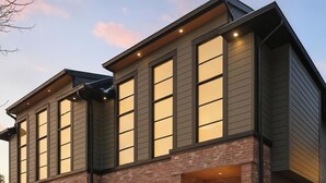 A two-story house with a brick facade, large windows, and a wooden garage door. - Modern Home with Spa Bath & Garage Altadore (Calgary)
