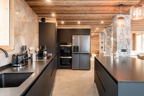 Eine moderne Küche mit dunklen Schränken, einem eingebauten Ofen und einer Wand mit Steinverkleidung.