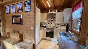 A compact kitchen with a tiled backsplash, wooden cabinets, a built-in oven, and a sink. - Chalet, wifi, balcony, parking, tv, 90m², Les Gets (Les Gets)