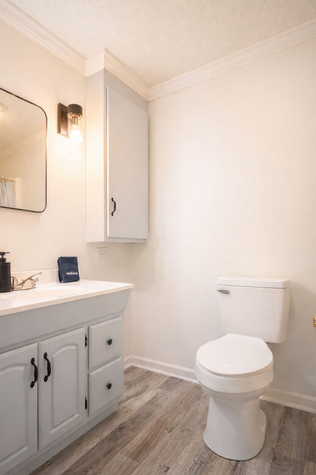 A bathroom with a white toilet, a sink with a towel, and a cabinet.