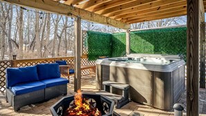 Un espace extérieur abrité comprenant un jacuzzi, un foyer et un canapé bleu.