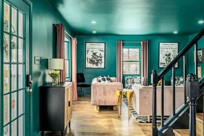Una habitación con paredes color turquesa, una escalera, una cama, un escritorio y una ventana.