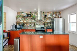 Una cocina con un salpicadero de colores, un refrigerador de acero inoxidable y una isla central con un fregadero.