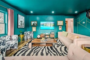 Un salón comedor con temática azul aguamarina, que incluye un sofá, sillones, una mesa de centro y obras de arte en las paredes.
