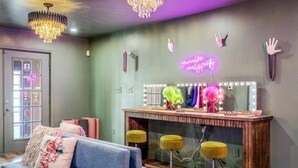 Une pièce dotée d’un miroir de coiffeuse, d’un néon et d’un lustre.
