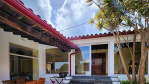 Una casa con techo rojo, una escalera que lleva a la entrada y un patio con mesa y sillas.