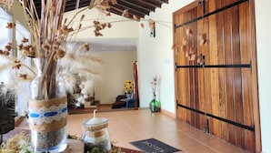 Techo de madera con diseño rústico, puerta de madera con manija de metal y suelo de baldosas.