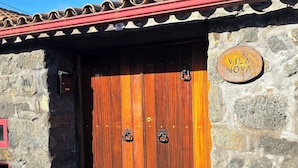Un edificio rústico con una puerta de madera y un muro de piedra.