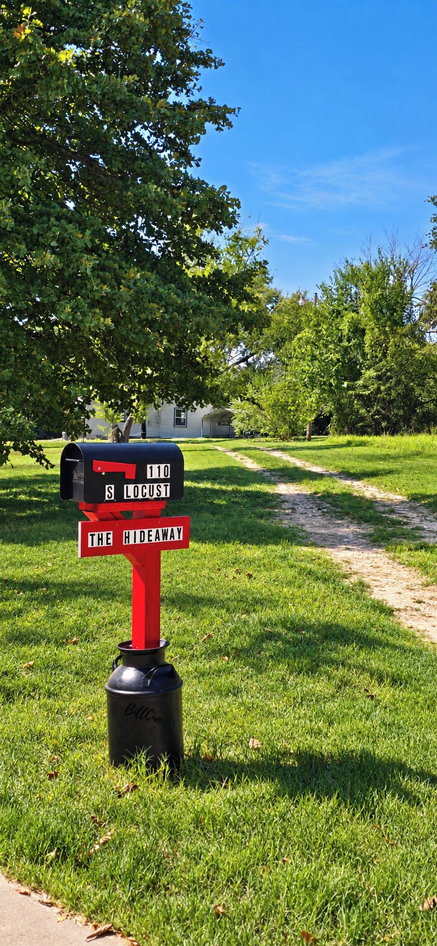 Une boîte aux lettres avec un poteau rouge et un corps noir, portant les inscriptions « 110 S LOCUST » et « THE HIDEAWAY », sur une pelouse verdoyante.
