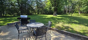 An outdoor patio with a grill, metal chairs, and a round table. - The Hideaway on Locust, 2 bedroom, pet friendly home in Lead Hill, Arkansas (Lead Hill)