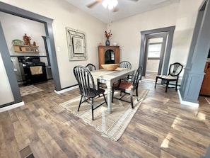 A dining area with a wooden table, black chairs, and a woven rug.