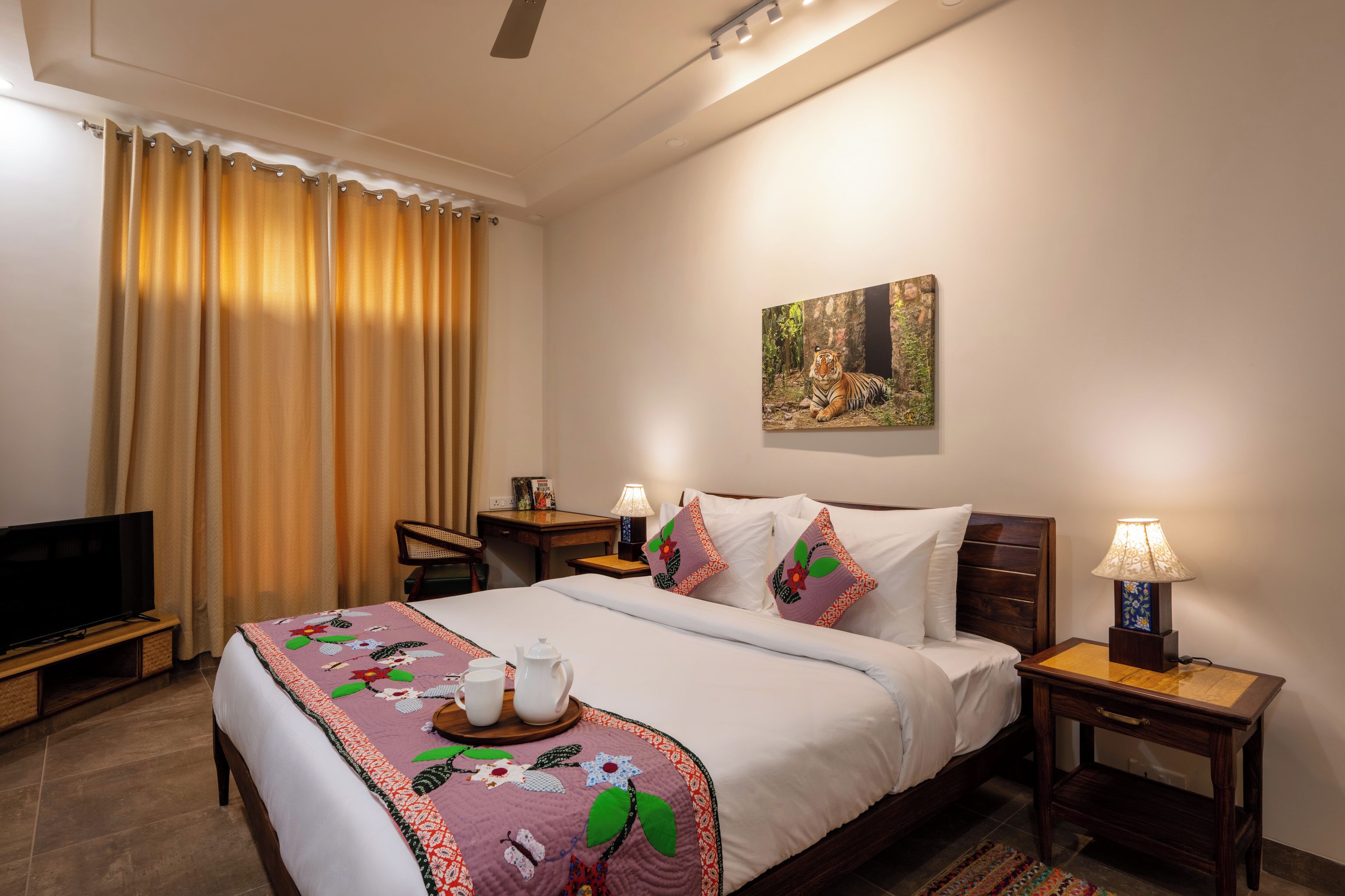 A hotel room with a bed, a television, a desk, and a painting on the wall.