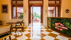 A hotel lobby with checkered flooring, a reception desk, a seating area, and a large painting of a building. - Seraibagh Ranthambore (Sawai Madhopur)