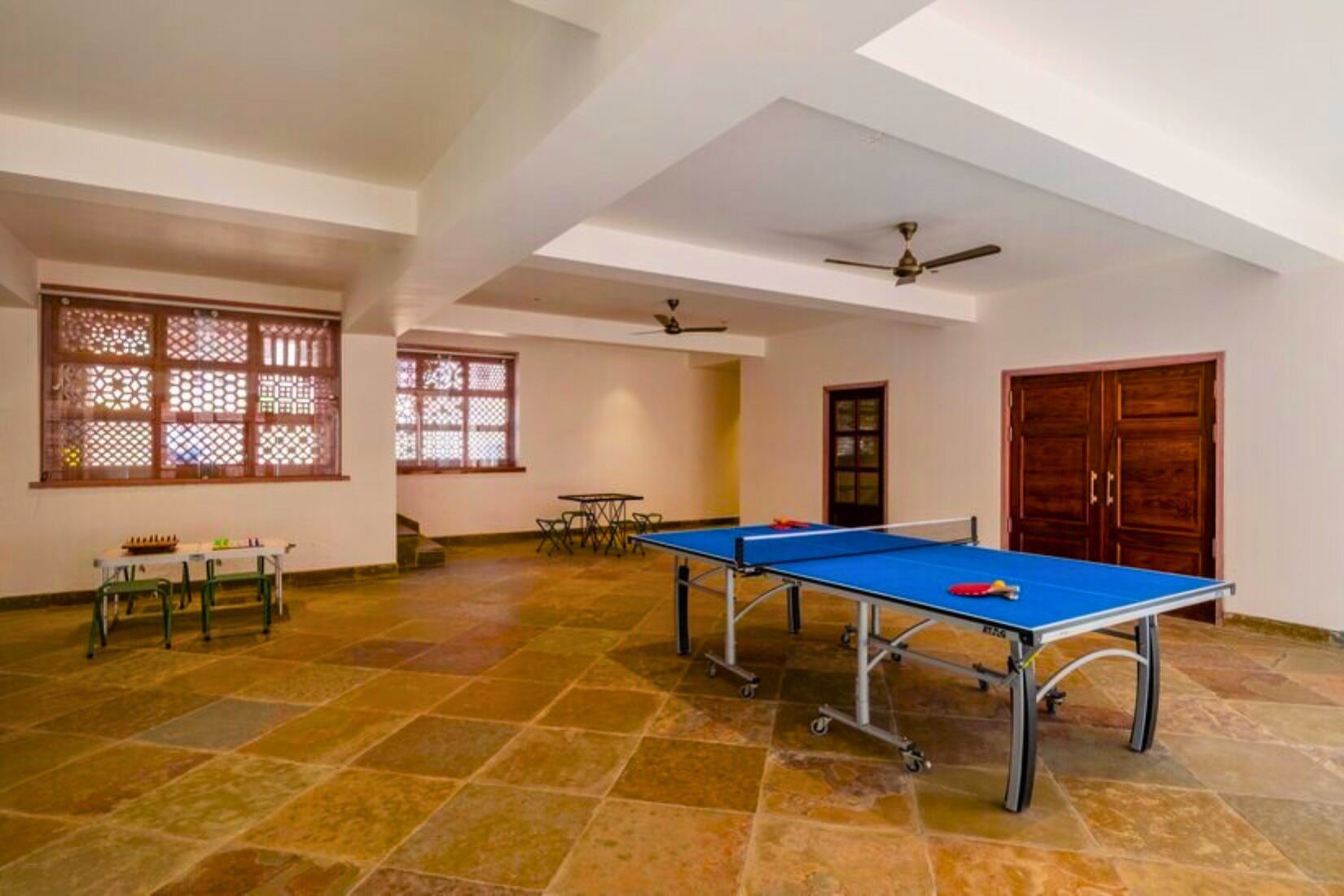A spacious room with a ping pong table, a small table with chairs, and a door.