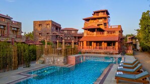 A hotel with a swimming pool, multiple buildings, and a bamboo fence. - Seraibagh Ranthambore (Sawai Madhopur)