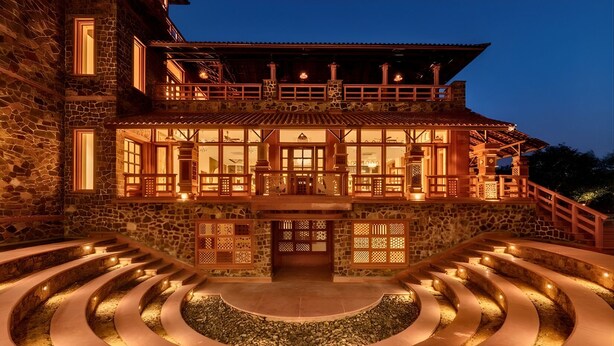 A stone building with a wooden balcony, a circular water feature, and a staircase leading to the entrance. - Seraibagh Ranthambore (Sawai Madhopur)