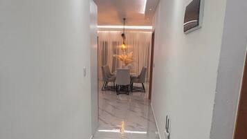 Un pasillo con piso de mármol que conduce a un comedor con una mesa y sillas.