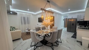 Ein modernes Wohnzimmer mit Essbereich, mit Marmorboden, zeitgemöbten Möbeln und einer einzigartigen Deckenleuchte.