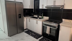 Eine moderne Küche mit weißen Schränken, einem Edelstahl-Kühlschrank, einem schwarzen Herd und einer schwarzen Mikrowelle.