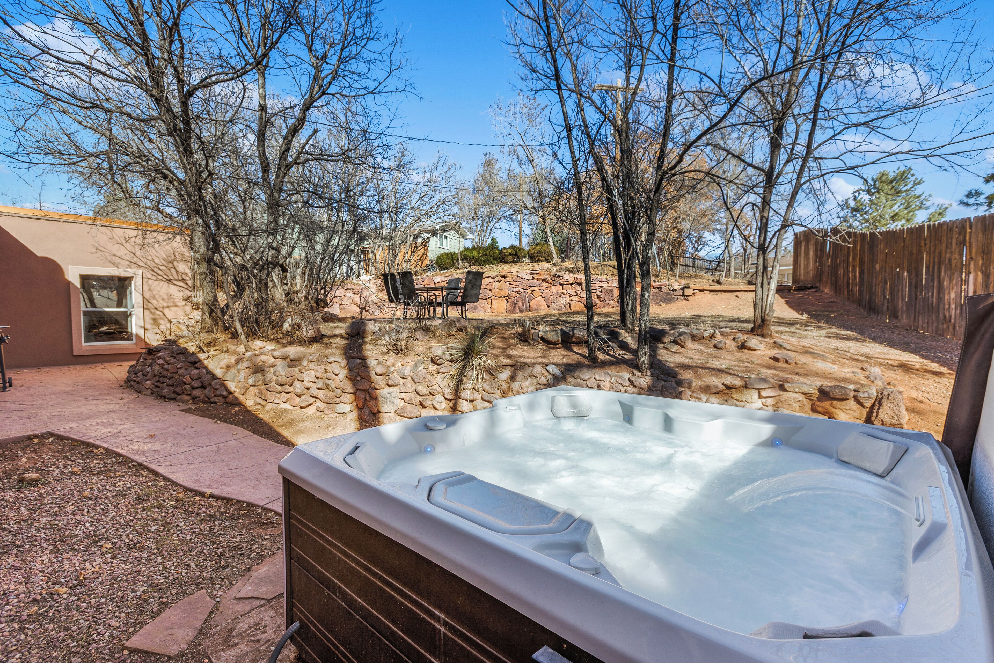 Een hottub in een achtertuin met terras, stenen muren en een houten omheining.