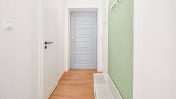 A narrow hallway with a wooden floor, a white door, and a green wall.