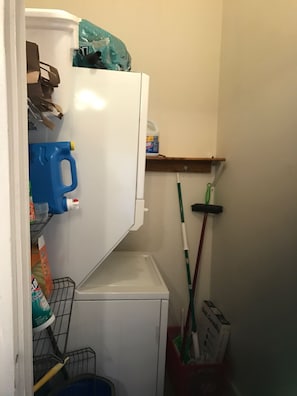 A small, white storage unit with shelves and a door, containing cleaning supplies and a mop. - 2-bedroom upstairs apartment in charming New Orleans near French Quarter (New Orleans)