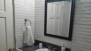 A bathroom with a white sink, a mirror, a toilet, and a towel rack.