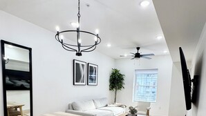 A modern living room with a wooden dining table, white sofa, and a ceiling fan. - Marvelous 3-bedroom/2 bath  apartment with AC in vibrant Newark (Newark)