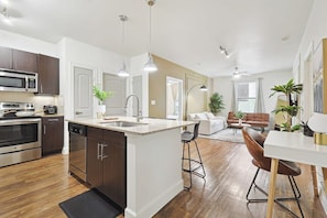 A modern kitchen with stainless steel appliances, a central island, and pendant lighting. - Luxurious 2B2B Near Toyota HQ (Frisco)
