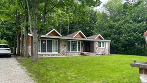 A two-story house with a stone facade, large windows, and a red front door. - The Quinta at Balm Beach (Perkinsfield)