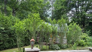 A stone wall with a wooden bench and a lantern. - The Quinta at Balm Beach (Perkinsfield)