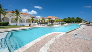 Ett semesterhotell med en swimmingpool, palmer och en byggnad med ett tak täckt av tegelpannor.