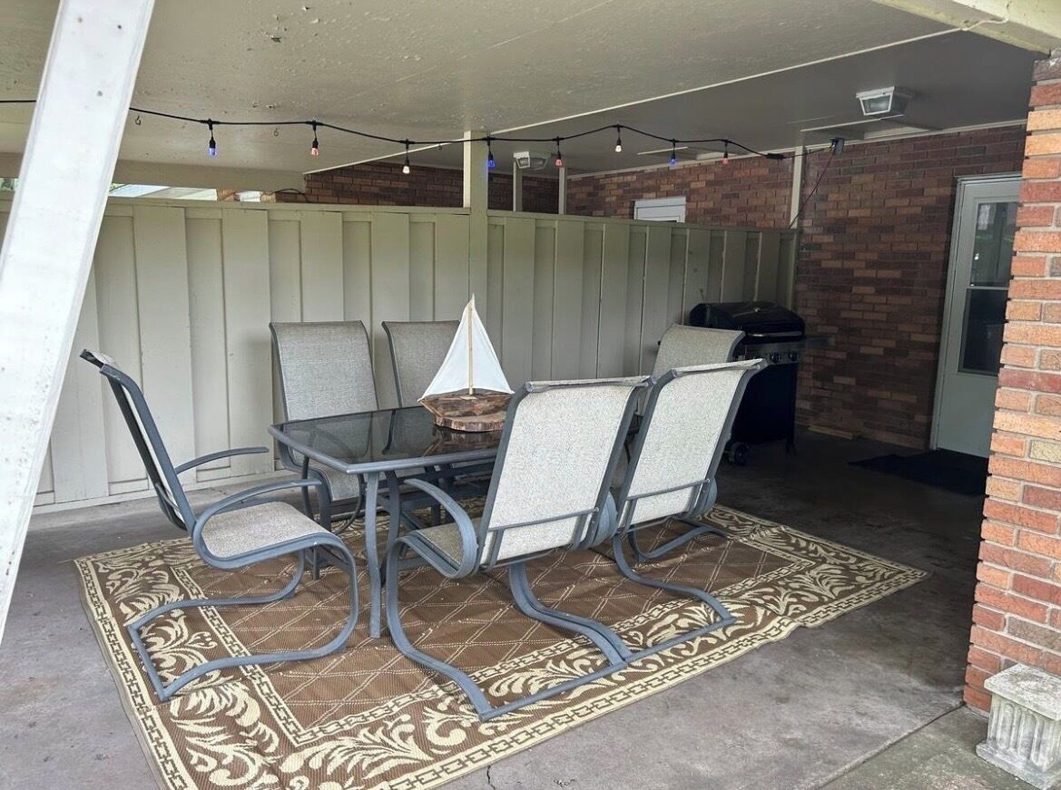 An outdoor patio with a table and chairs, a grill, and a decorative sail.