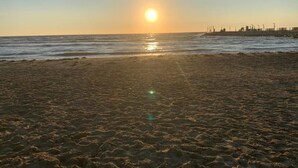 Une plage où le soleil se couche sur l’eau, créant une atmosphère paisible.