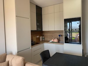 A compact kitchen with white cabinets, a wooden countertop, and a window with a view of the outdoors. - Fully furnished, New stylish One Bedroom apartment - 120 meters from the beach. (Golem)