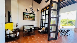 A spacious patio with tiled flooring, a large window with a view, and a hanging chandelier. - Finca La Guadalupe - The Pearl of the Southwest (Tarso)