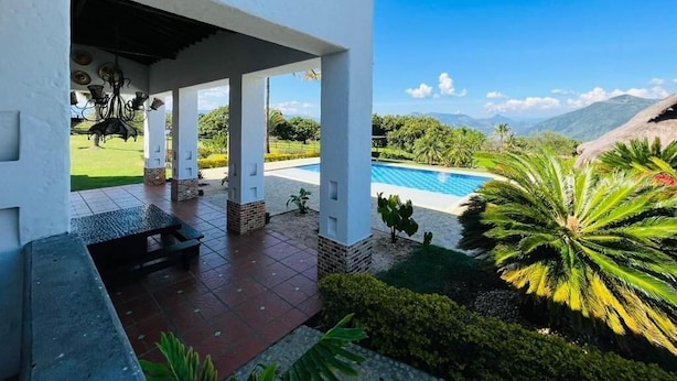 A covered outdoor area with a pool, palm trees, and a view of mountains. - Finca La Guadalupe - The Pearl of the Southwest (Tarso)