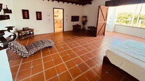 A room with a tiled floor, a bed, a motorcycle, and a door leading to another room. - Finca La Guadalupe - The Pearl of the Southwest (Tarso)