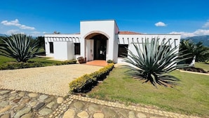 A modern building with a white facade, a red-tiled roof, and a stone-paved entrance. - Finca La Guadalupe - The Pearl of the Southwest (Tarso)