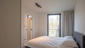 Ein Schlafzimmer mit Bett, einem Vorhangfenster, einer Tür und einer Deckenleuchte.