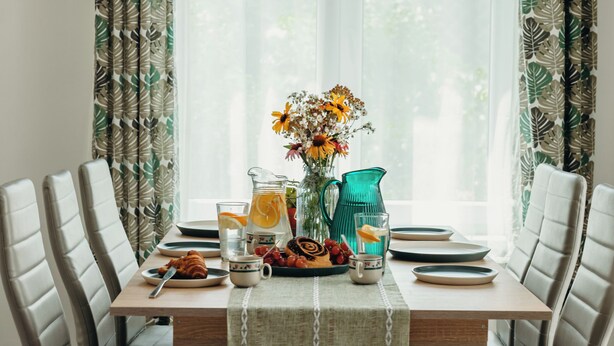 A dining table with four chairs, a vase with flowers, a pitcher, and plates with food. - Cozy vacation house near Lake Balaton in Vonyarcvashegy (Vonyarcvashegy)