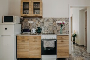 Cucina con forno a microonde, tostapane, bollitore e forno. Dispensa con mobili in legno e zoccolo a mosaico.