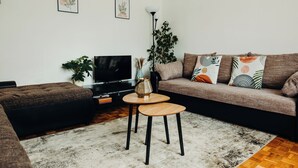 A modern living room with a brown sofa, a small wooden table, and a TV. - Cozy vacation house near Lake Balaton in Vonyarcvashegy (Vonyarcvashegy)