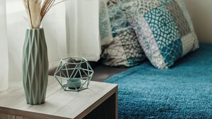 A bedroom with a bed covered in a blue blanket, a bedside table with a vase of dried plants, and a geometric metal sculpture. - Cozy vacation house near Lake Balaton in Vonyarcvashegy (Vonyarcvashegy)