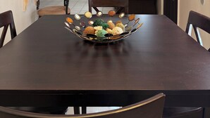 Ein Esszimmer mit einem dunklen Holztisch, Stühlen, einer Kronleuchter, einem Deckenventilator und einem an der Wand montierten Fernseher.